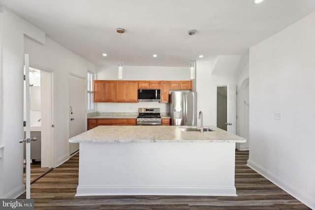 kitchen featuring appliances with stainless steel finishes, hanging light fixtures, an island with sink, and dark hardwood / wood-style flooring