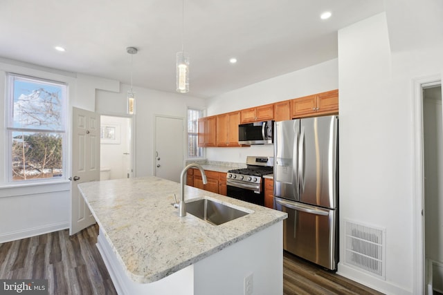 kitchen with stainless steel appliances, a center island with sink, sink, and pendant lighting