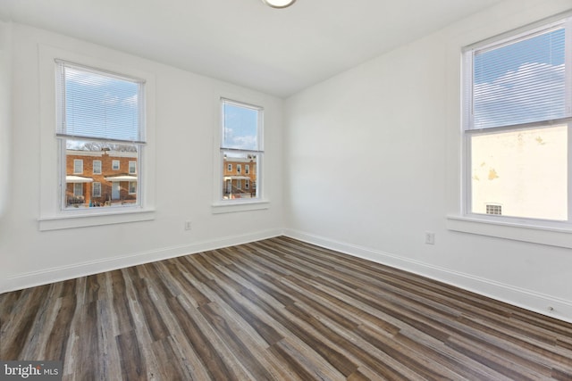 spare room with plenty of natural light and dark wood-type flooring