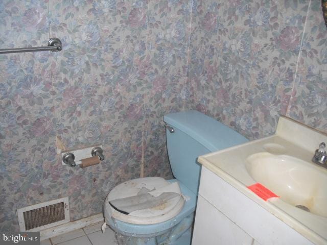 bathroom with toilet, vanity, and tile patterned flooring