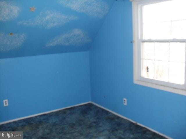 bonus room featuring lofted ceiling and dark colored carpet