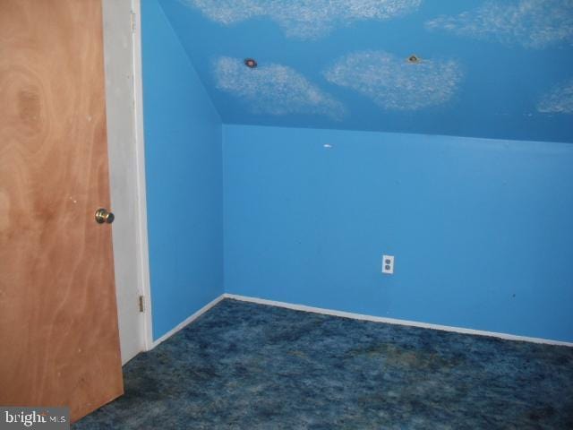 additional living space featuring lofted ceiling and dark carpet