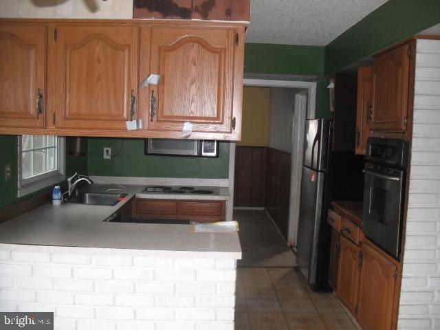 kitchen featuring kitchen peninsula, black oven, a textured ceiling, electric stovetop, and sink