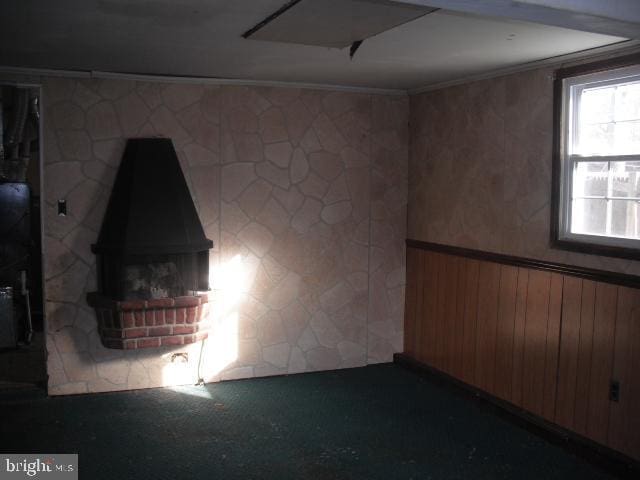 carpeted empty room with ornamental molding and wood walls