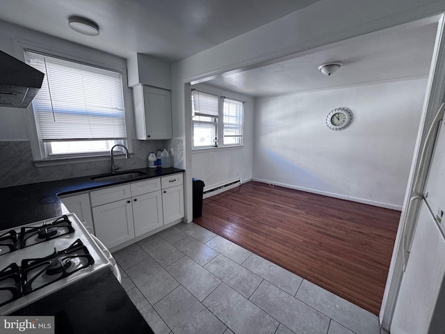 kitchen with baseboard heating, light tile patterned floors, sink, white cabinetry, and tasteful backsplash