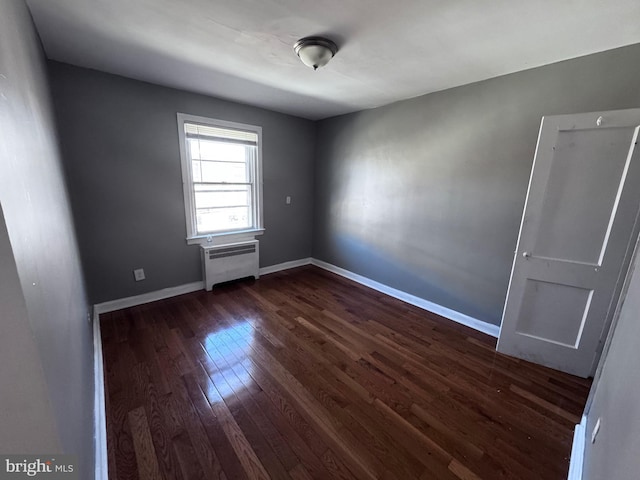 spare room with dark hardwood / wood-style flooring and radiator heating unit