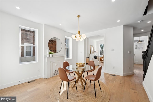 dining room with light hardwood / wood-style floors and a notable chandelier