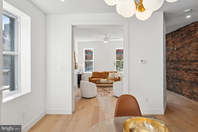 dining area with ceiling fan, brick wall, and light hardwood / wood-style flooring