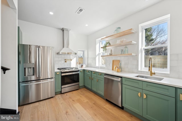 kitchen featuring appliances with stainless steel finishes, wall chimney range hood, tasteful backsplash, sink, and plenty of natural light