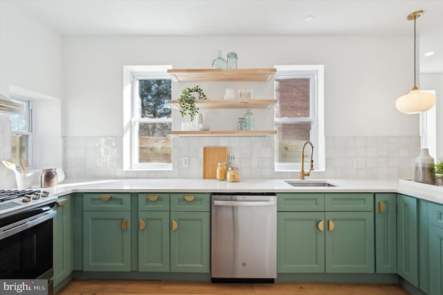 kitchen with appliances with stainless steel finishes, decorative backsplash, green cabinetry, pendant lighting, and sink