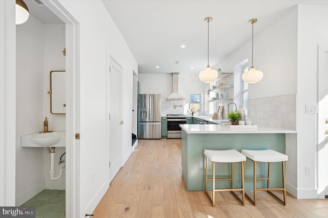 kitchen featuring kitchen peninsula, decorative backsplash, hanging light fixtures, and stainless steel appliances