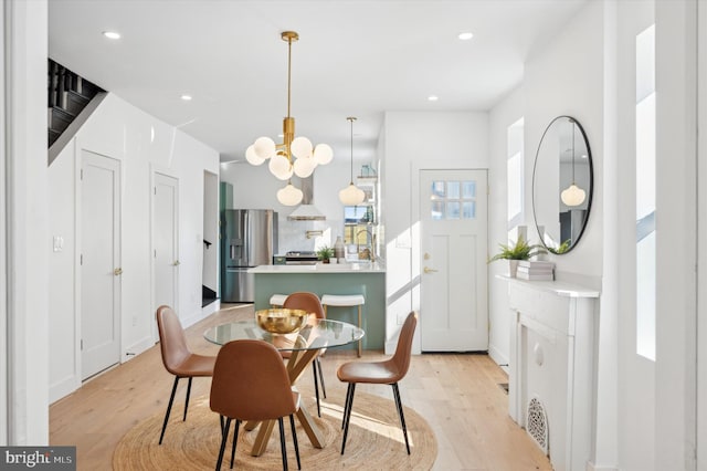 dining space featuring light hardwood / wood-style flooring, an inviting chandelier, and a healthy amount of sunlight