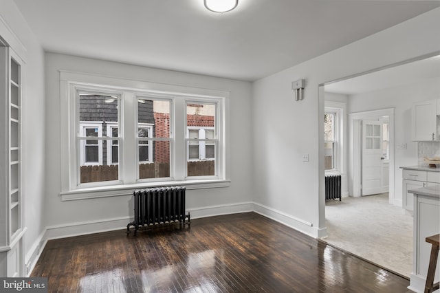 unfurnished room featuring radiator and dark hardwood / wood-style flooring