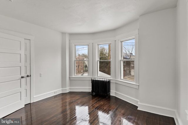 empty room featuring dark hardwood / wood-style flooring and radiator heating unit