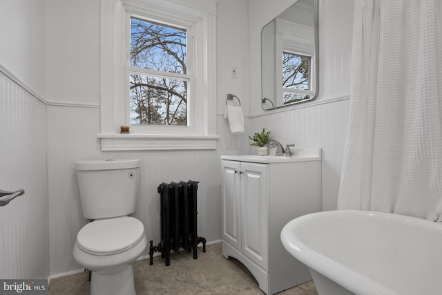 bathroom with radiator, toilet, a bath, and vanity