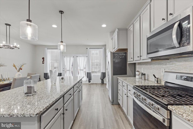 kitchen with decorative light fixtures, a center island, stainless steel appliances, light hardwood / wood-style floors, and backsplash