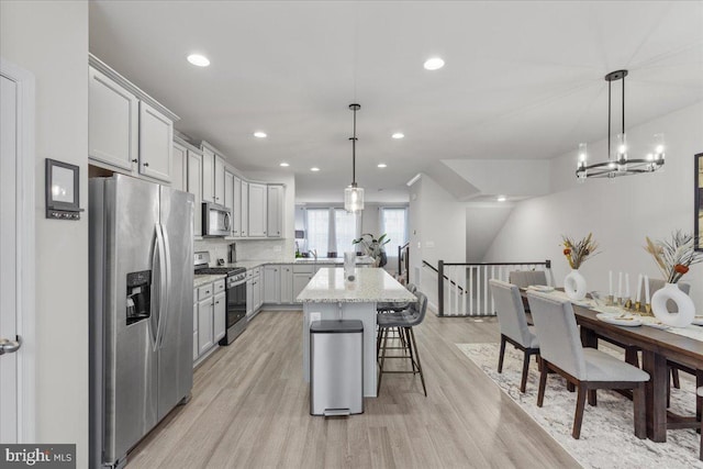 kitchen featuring hanging light fixtures, a kitchen bar, a center island, and appliances with stainless steel finishes