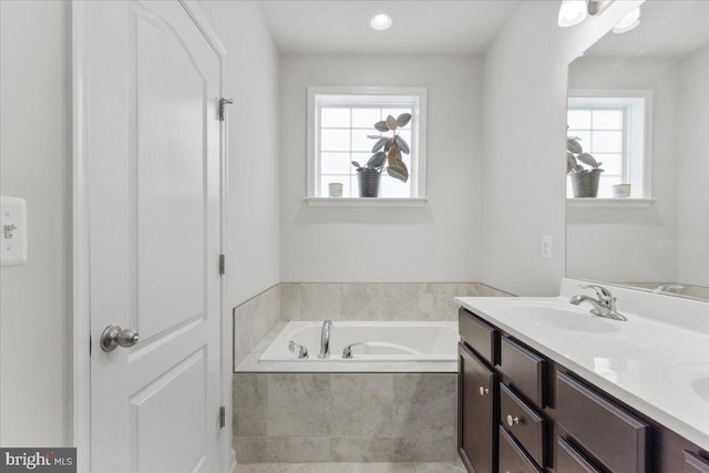 bathroom featuring vanity and tiled bath