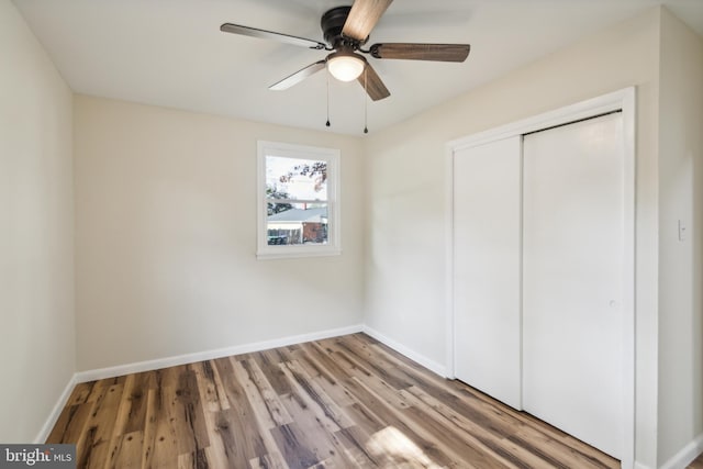 unfurnished bedroom featuring ceiling fan, a closet, and wood-type flooring