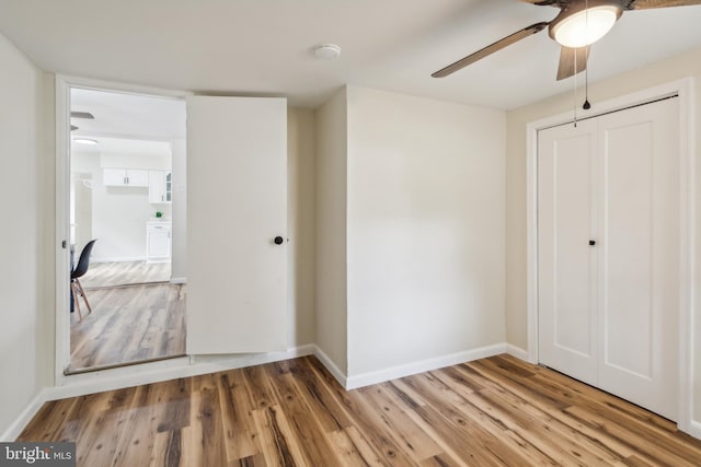 unfurnished bedroom featuring hardwood / wood-style floors, a closet, and ceiling fan