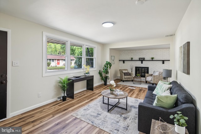 living room featuring a brick fireplace and hardwood / wood-style flooring