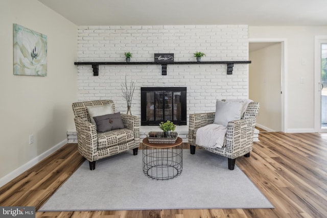 living area with a brick fireplace and hardwood / wood-style flooring