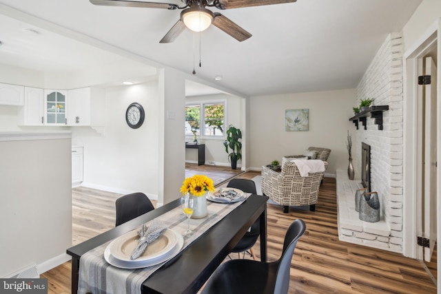 dining space featuring a fireplace, ceiling fan, and hardwood / wood-style flooring