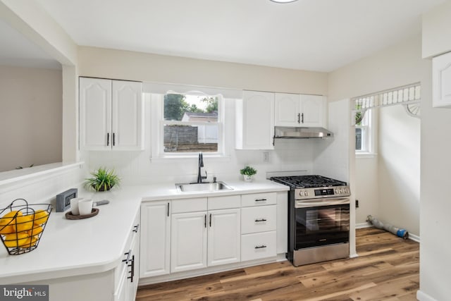 kitchen with hardwood / wood-style flooring, stainless steel range with gas cooktop, tasteful backsplash, white cabinets, and sink