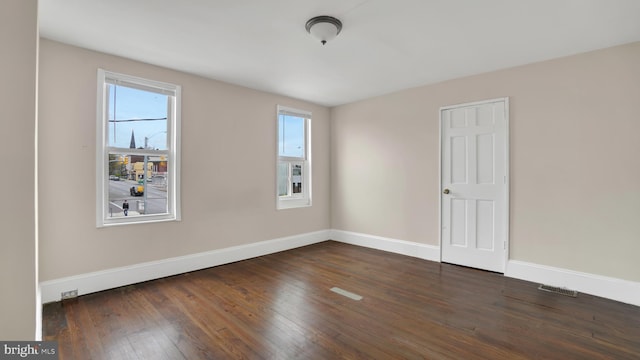 empty room with a healthy amount of sunlight and dark hardwood / wood-style flooring