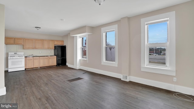 kitchen featuring white range, black fridge, light brown cabinetry, and dark wood-type flooring