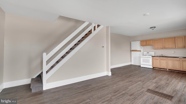 kitchen with light brown cabinets, white gas range oven, and dark hardwood / wood-style floors