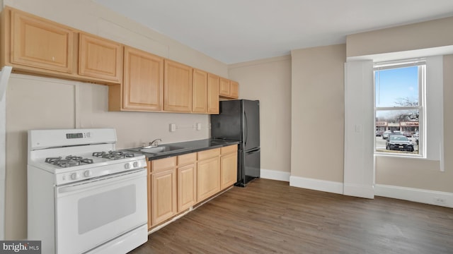 kitchen featuring black refrigerator, light brown cabinets, white range with gas stovetop, dark hardwood / wood-style flooring, and sink