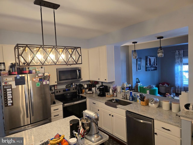 kitchen with light stone counters, decorative light fixtures, white cabinets, appliances with stainless steel finishes, and sink