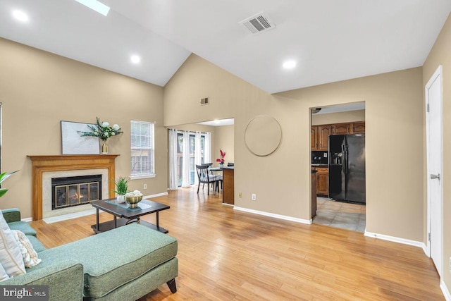 living room featuring high vaulted ceiling and light hardwood / wood-style floors