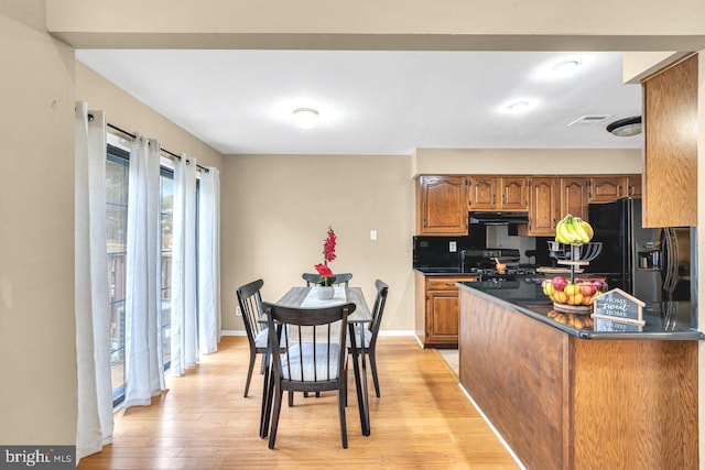 kitchen featuring range, light wood-type flooring, ventilation hood, decorative backsplash, and black fridge with ice dispenser