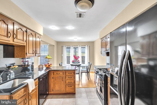 kitchen featuring sink, light tile patterned floors, black appliances, and kitchen peninsula