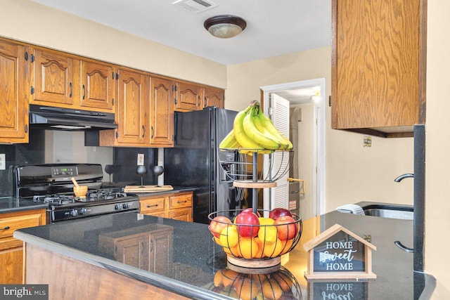 kitchen featuring black appliances, dark stone counters, and sink