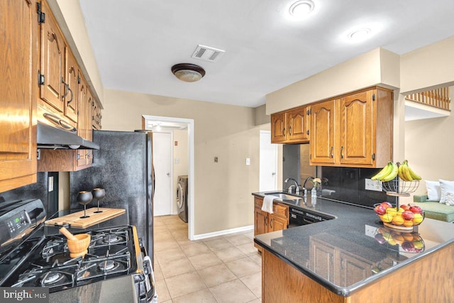 kitchen with dishwasher, kitchen peninsula, stainless steel gas range oven, washer / dryer, and tasteful backsplash