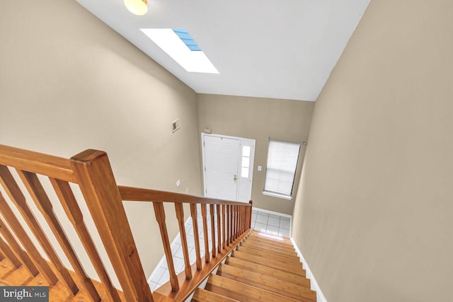 staircase with wood-type flooring and vaulted ceiling with skylight