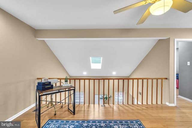 living area with ceiling fan, lofted ceiling with skylight, and wood-type flooring