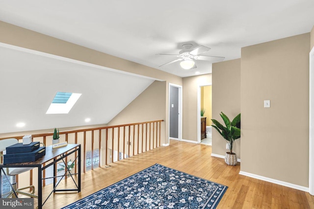 corridor with vaulted ceiling with skylight and hardwood / wood-style flooring