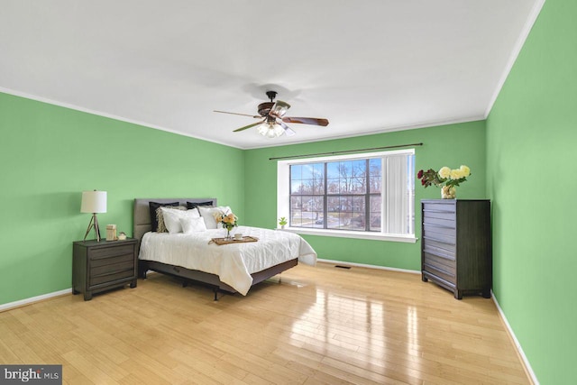 bedroom featuring ceiling fan, crown molding, and light wood-type flooring