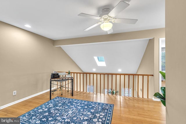 sitting room featuring hardwood / wood-style flooring, ceiling fan, and vaulted ceiling with skylight