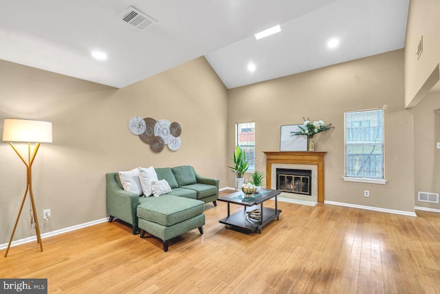 living room with high vaulted ceiling and light hardwood / wood-style flooring