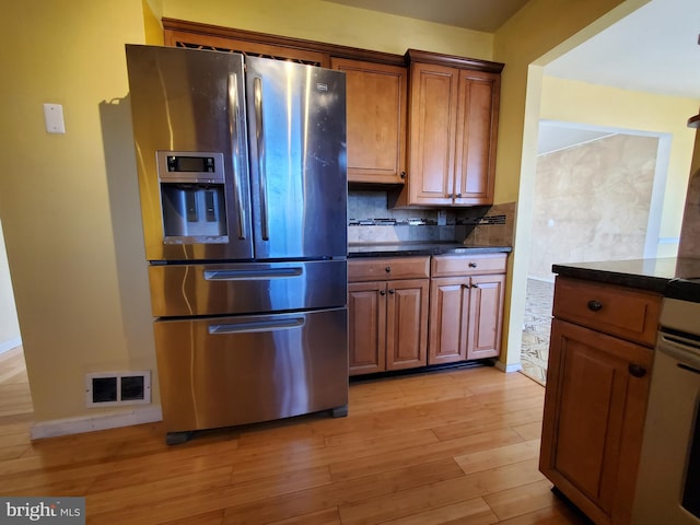 kitchen with stainless steel fridge, light hardwood / wood-style flooring, and decorative backsplash