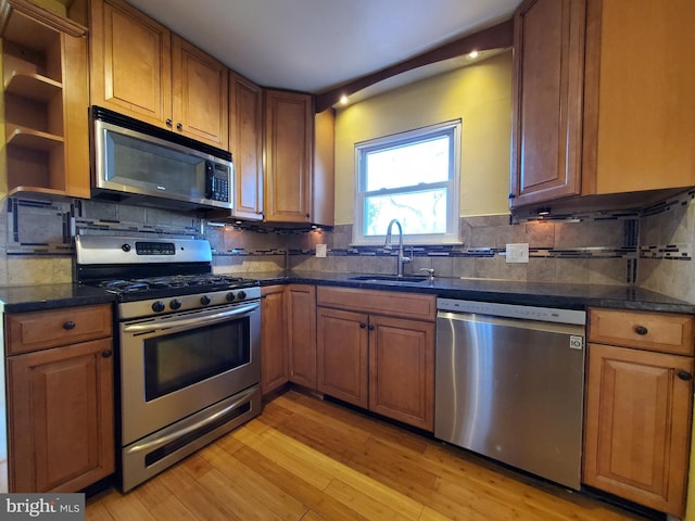 kitchen with appliances with stainless steel finishes, light hardwood / wood-style floors, tasteful backsplash, and sink