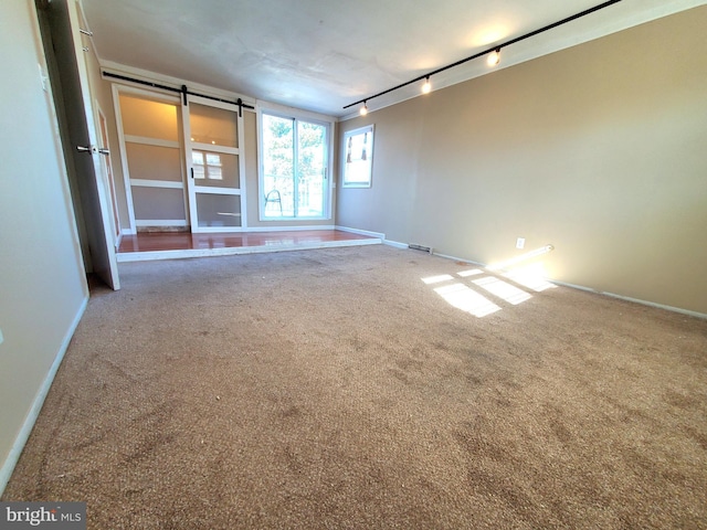 unfurnished living room featuring a barn door, carpet flooring, and rail lighting