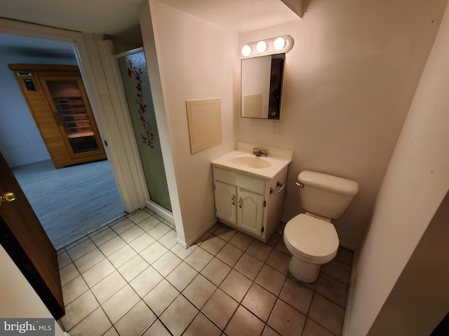 bathroom featuring toilet, vanity, tile patterned flooring, and a shower with shower door