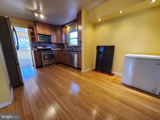 kitchen with stainless steel appliances, light hardwood / wood-style floors, decorative backsplash, and sink