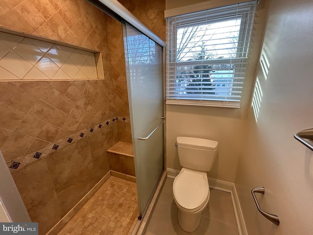 bathroom featuring toilet, a shower with door, and tile patterned flooring